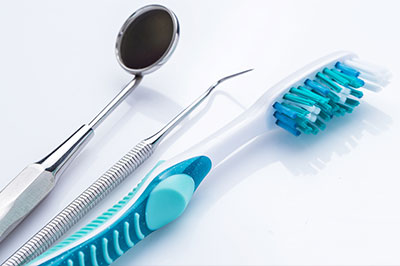 The image shows dental tools including a toothbrush with blue bristles, dental floss, and a pair of scissors, all arranged on a white background.