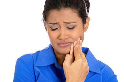 The image shows a woman with her eyes closed, holding her nose, seemingly distressed or experiencing discomfort.