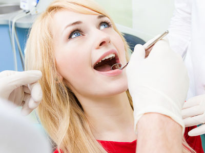 A woman receiving dental care while smiling at the camera.