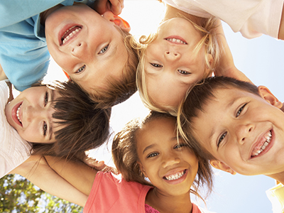 A group of children smiling and posing together with their arms around each other.